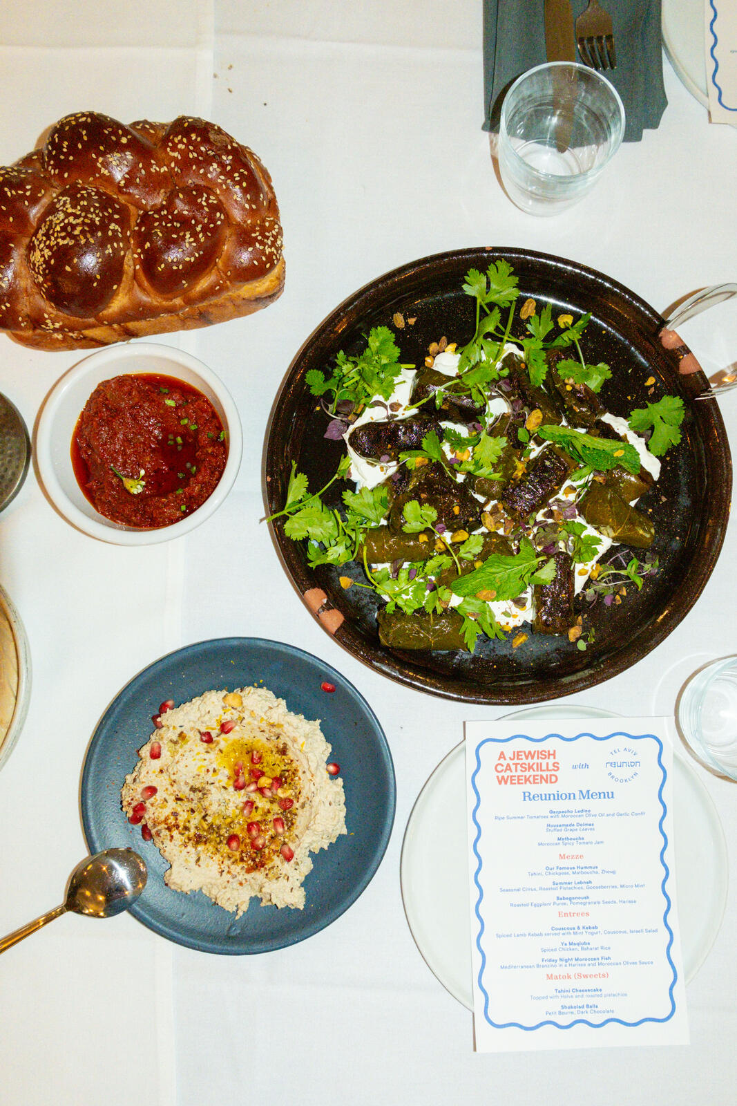 Reunion menu beside challah and shared dishes for A Jewish Catskills Weekend